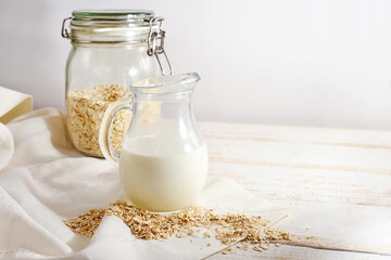Vegan oat milk, a healthy alternative without animal dairy products in a glass jug on a light...