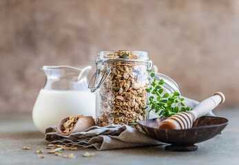 Homemade granola or muesli with pumpkin seeds, honey and milk on concrete background. Healthy...