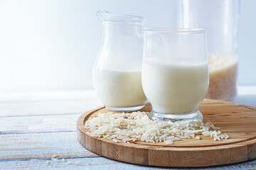 Vegan rice milk, healthy alternative without animal dairy products in a drinking glass and a jug on...