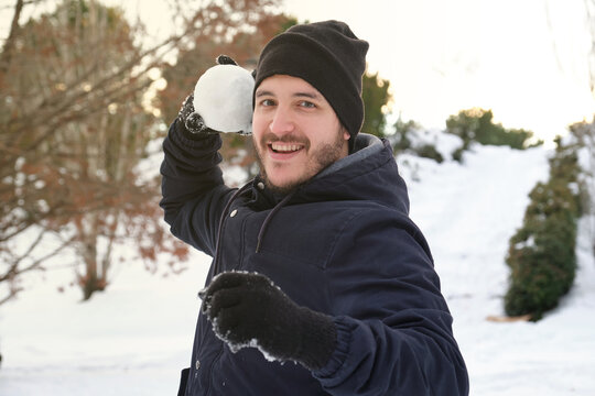 Young caucasian man ready to throw a snowball in a park