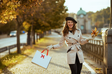 happy young woman with shopping bags and autumn yellow leaves