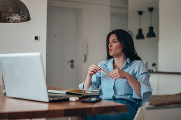 Businesswoman using a laptop and a business planner in an office