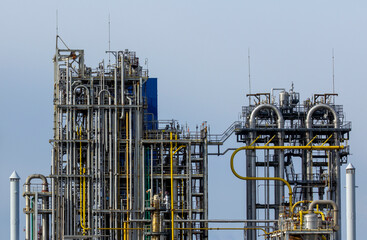 Technological installation of an oil and gas factory complex against a blue cloudless sky.