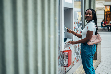 Cheerful african american woman using atm machine