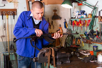 Gunsmith checks Kalashnikov assault rifle in a weapons workshop