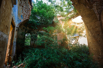 Old ancient abandoned red brick ruins overgrown by plants