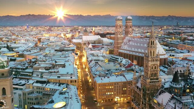 Germany Munich skyline aerial view at winter with snow, fly over munich marienplatz sqaure frauenkirche town hall in old town city centre in bachround alps mountains at sunrise.