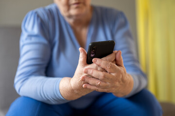 Elderly woman fingering fingers looking at smartphone