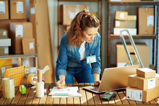 young female in jeans with laptop in warehouse