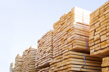 Stacked stacks of wooden planks against the sky. Lumber warehouse, wood drying. Lumber for construction.