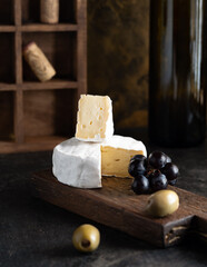 wine appetizer: cheese, olives and grapes are on the table next to a bottle of wine. High quality photo