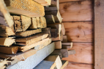 Old sawn pine boards stacked, piled near the wall used as firewood