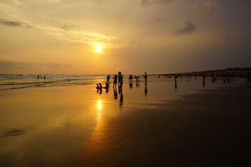 Selective low angle shot of silhouettes of beachgoers enjoying the sunset at Parangtritis beach, Yogyakarta