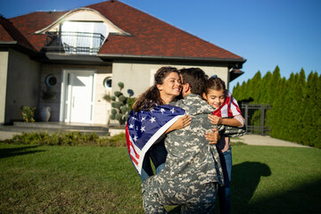 Soldier in uniform coming home and his lovely family with American flag running into his arms...