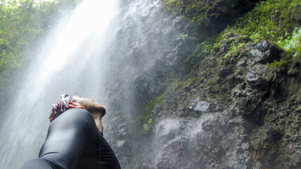 A man standing bellow the waterfall and looking up to the waterfall, Kauai, Hawaii