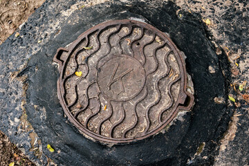 round iron rusty hatch on sidewalk closeup of city drainage system canalization top view