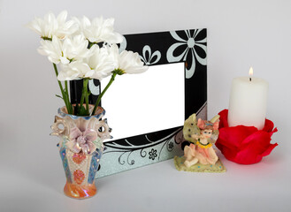 horizontal photo frame with a candle and a bouquet of chrysanthemums in a vase on a white background