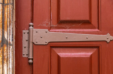 Detail of a red painted wooden door with iron hinges