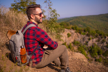 Naklejka na ściany i meble man wearing checkered shirt smiling and sitting on the cliff