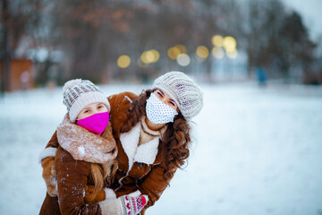 happy stylish mother and child outdoors in city park in winter