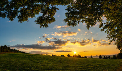 Obraz premium Landschaft bei Sonnenuntergang, Wiese, Sonne, Hügel
