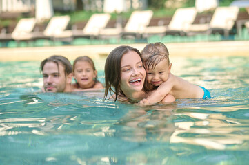 A young family having fun in a pool and looking enjoyed