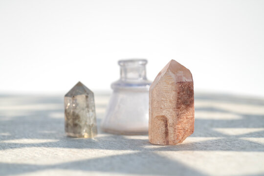  Lemurian and Smokey quartz points with a vintage bottle in a mandala shadow pattern.   Natural object still life photography.