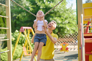 Man supporting little daughter exercising on tightrope