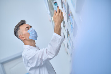 Pharmacist in protective mask considering medication with interest