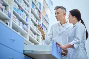 Man and woman interestedly considering medicine in pharmacy