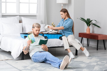 Obraz premium Couple of tourists packing suitcase at home