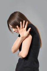 Scared young woman on grey background. Concept of harassment