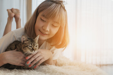 young asian woman playing with cat in living room at home