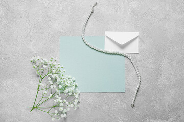 Blank card with envelope, flowers and necklace on light background