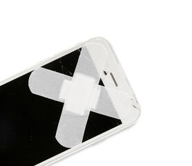 Mobile phone with broken screen and medical plasters on white background, closeup