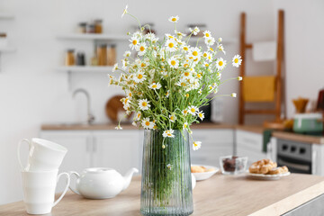 Vase with chamomiles on table in kitchen