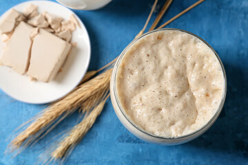 Glass jar with fresh sourdough on blue background