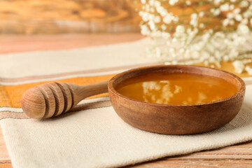 Fototapeta premium Bowl of sweet honey and dipper on wooden table
