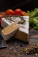 brie cheese on wood with rosemary and cherry tomato