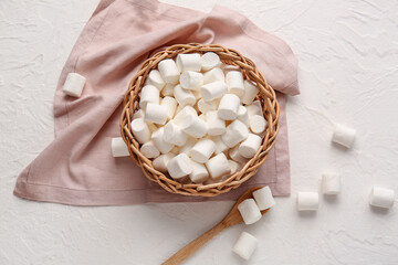 Wicker basket with tasty marshmallows on light background