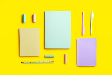 Stylish notebooks, pens, pencil and erasers on color background