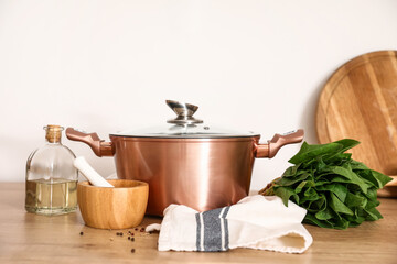 Cooking pot with mortar, pestle, spinach and oil on kitchen counter