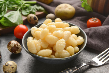 Bowl with tasty gnocchi on dark background