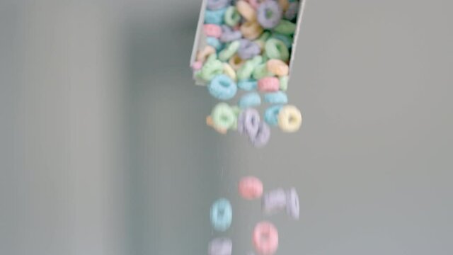 Breakfast cereals in the form of colorful corn rings are poured out of the package. Food close - up of Colored corn flakes and dairy products. Slow motion. High quality 4k footage