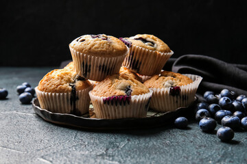 Composition with tasty blueberry muffins and berries on dark background