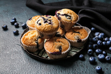 Composition with tasty blueberry muffins and berries on dark background