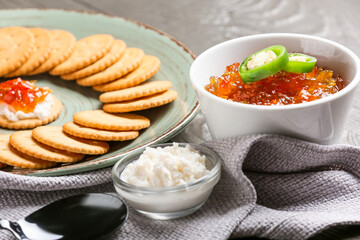Delicious jalapeno pepper jam, cottage cheese and crackers on grey wooden table