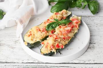 Plate with quinoa stuffed zucchini boats on light wooden background