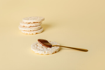 Crunchy rice crackers with melted chocolate on color background