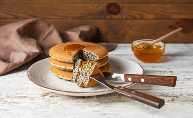 Plate of tasty pancakes with honey on table